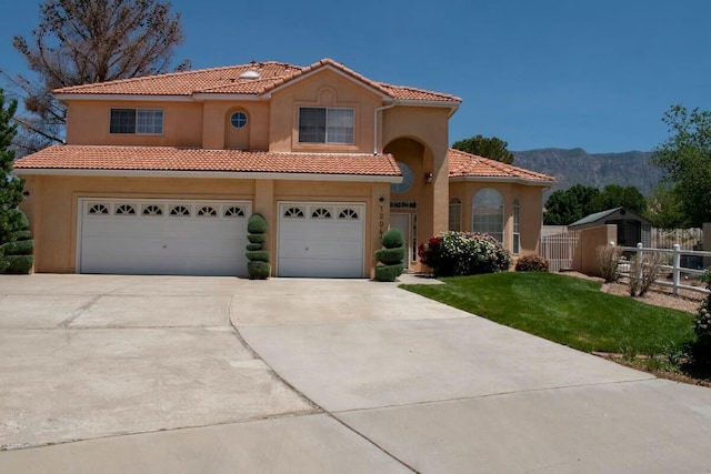 mediterranean / spanish home with a tile roof, a mountain view, driveway, fence, and an attached garage