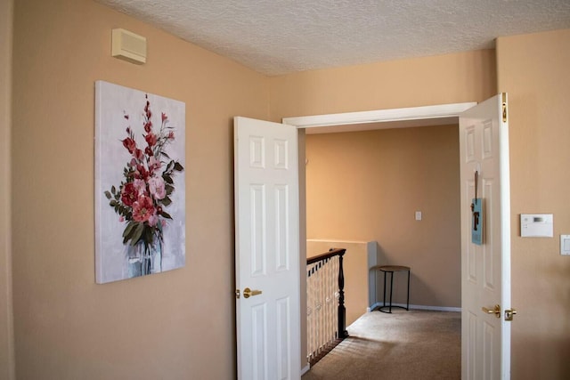hallway featuring baseboards, carpet, and a textured ceiling