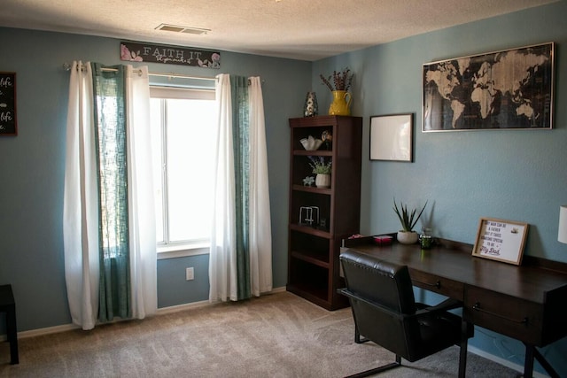 carpeted home office with a textured ceiling, plenty of natural light, visible vents, and baseboards
