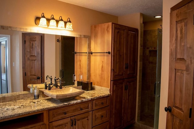 bathroom featuring vanity, a textured ceiling, and a shower stall