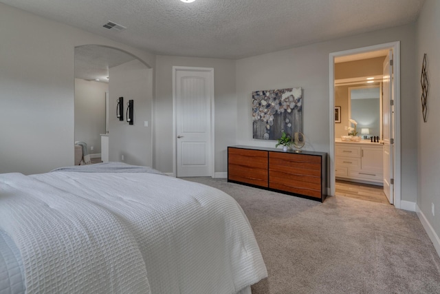 1954 Castle Peak Loop NE, Rio Rancho, NM 87144 - bedroom with arched walkways, light carpet, a textured ceiling, and ensuite bath