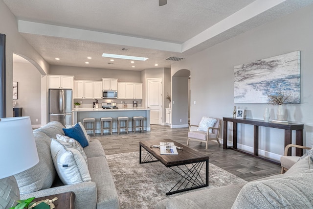 1954 Castle Peak Loop NE, Rio Rancho, NM 87144 - living room featuring arched walkways, a textured ceiling, dark wood-style floors, and recessed lighting
