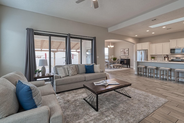 1954 Castle Peak Loop NE, Rio Rancho, NM 87144 - living room featuring arched walkways, light wood-style flooring, a ceiling fan, a textured ceiling, and recessed lighting