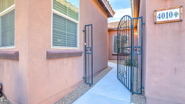 doorway to property with stucco siding, a gate, and a tile roof