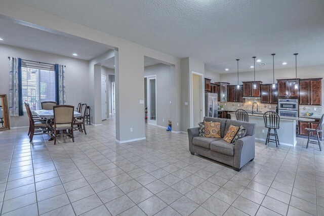living room with light tile patterned floors, recessed lighting, a textured ceiling, and baseboards