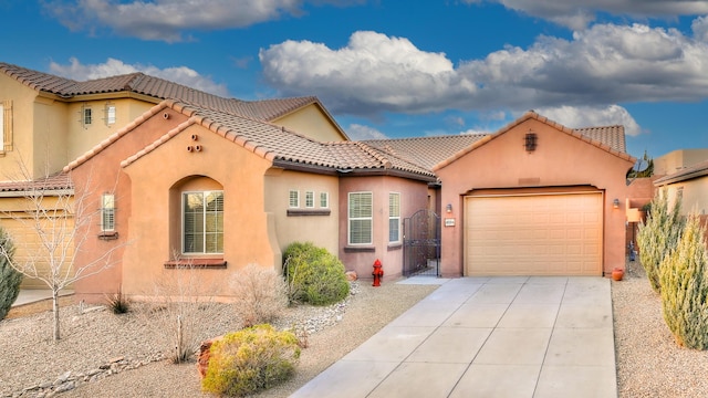 mediterranean / spanish house featuring a gate, a tiled roof, concrete driveway, and stucco siding