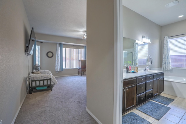bathroom with a sink, double vanity, baseboards, ceiling fan, and a garden tub