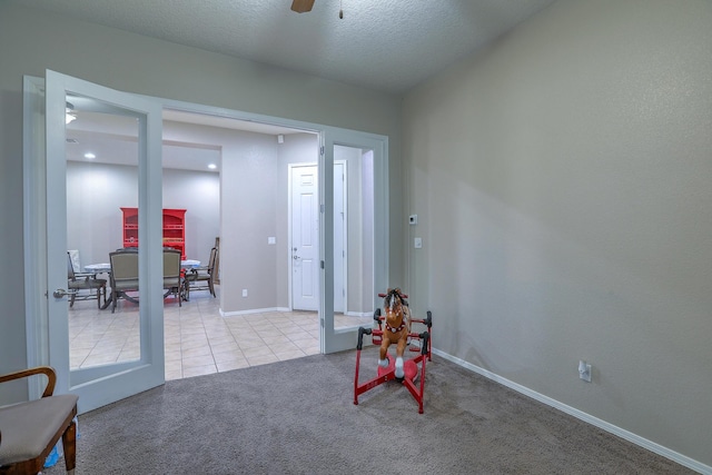 interior space featuring ceiling fan, carpet flooring, tile patterned flooring, and baseboards