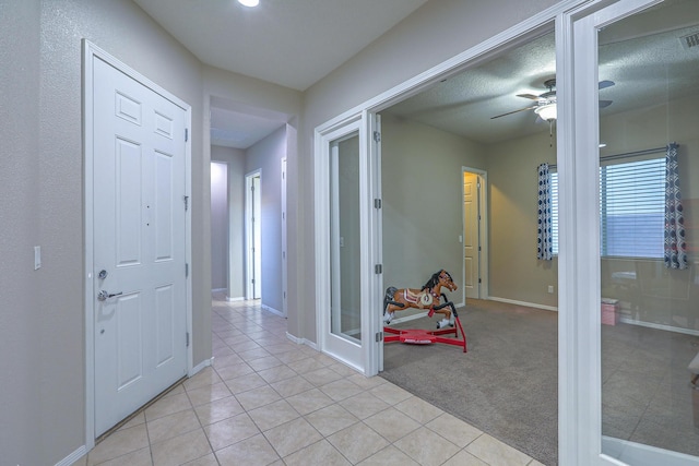 hall featuring light tile patterned floors and baseboards