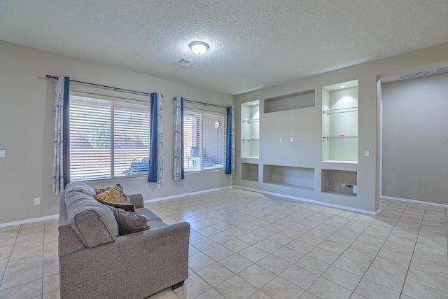 living area featuring baseboards, light tile patterned floors, built in shelves, and a textured ceiling