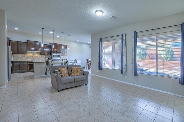 living area with light tile patterned flooring, visible vents, and baseboards