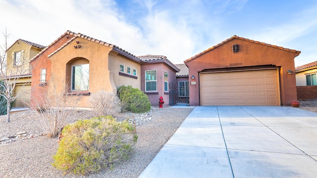 mediterranean / spanish home with a garage, a tile roof, driveway, and stucco siding