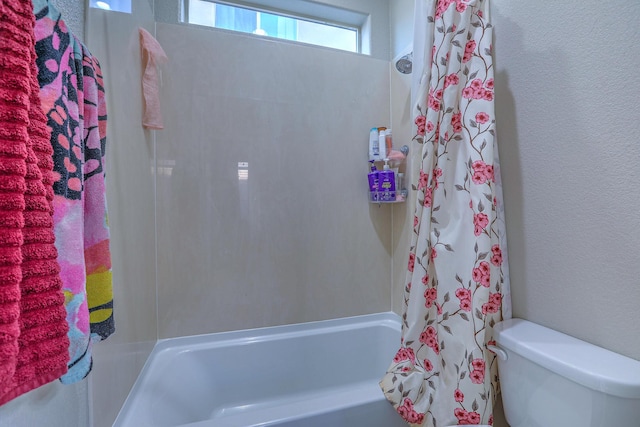 bathroom featuring shower / bath combination with curtain, toilet, and a textured wall