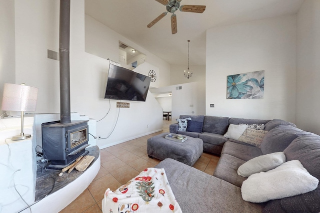 living area with a wood stove, visible vents, ceiling fan, and tile patterned flooring