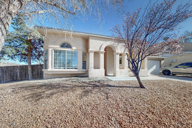 view of front of house featuring driveway, stucco siding, an attached garage, and fence