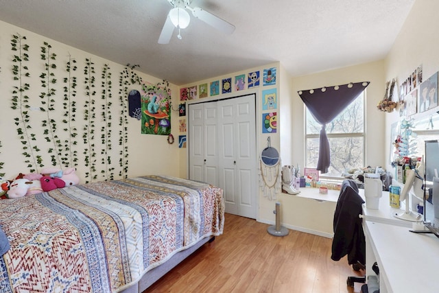 bedroom with a closet, a ceiling fan, a textured ceiling, light wood-type flooring, and baseboards