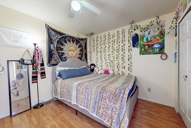 bedroom with baseboards, a textured ceiling, wood finished floors, and a ceiling fan