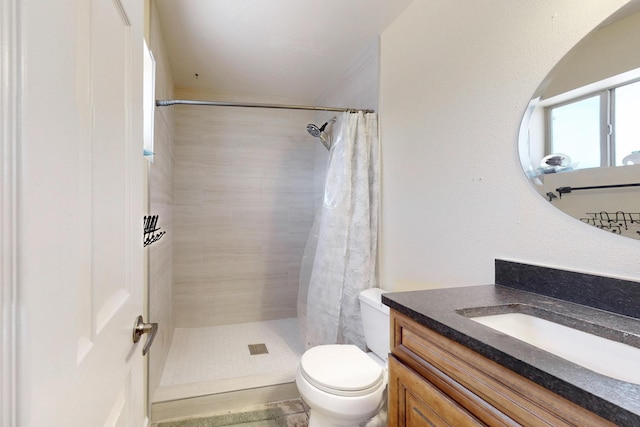 bathroom featuring a tile shower, toilet, and vanity