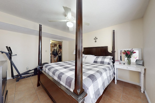 bedroom with a spacious closet, baseboards, light tile patterned flooring, a ceiling fan, and a closet