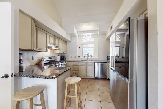 kitchen featuring a sink, appliances with stainless steel finishes, a peninsula, cream cabinets, and under cabinet range hood