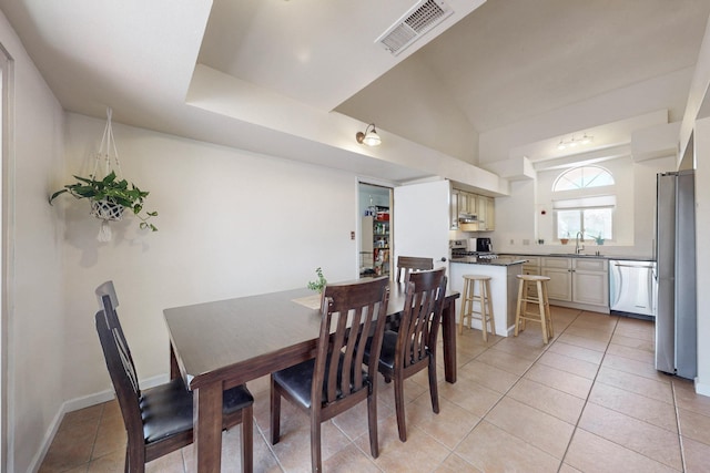 dining area featuring light tile patterned flooring, baseboards, lofted ceiling, and visible vents