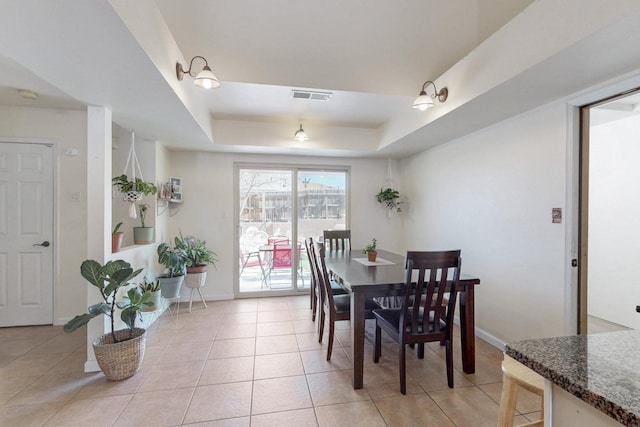 dining space featuring a raised ceiling, light tile patterned floors, baseboards, and visible vents