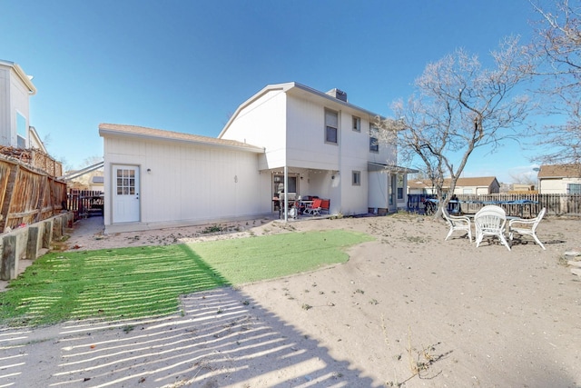 back of house with a chimney, a fenced backyard, and a yard