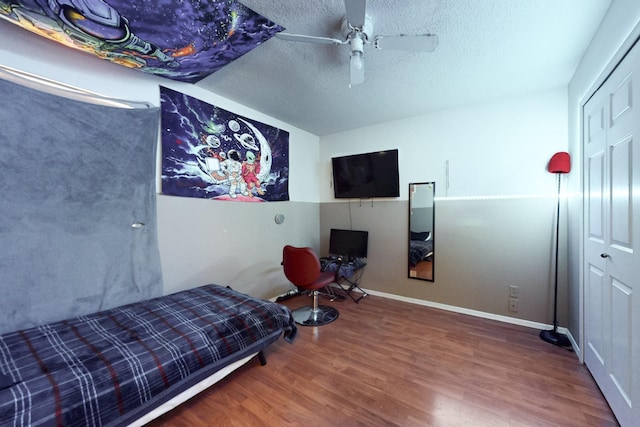bedroom featuring a ceiling fan, a closet, wood finished floors, and a textured ceiling