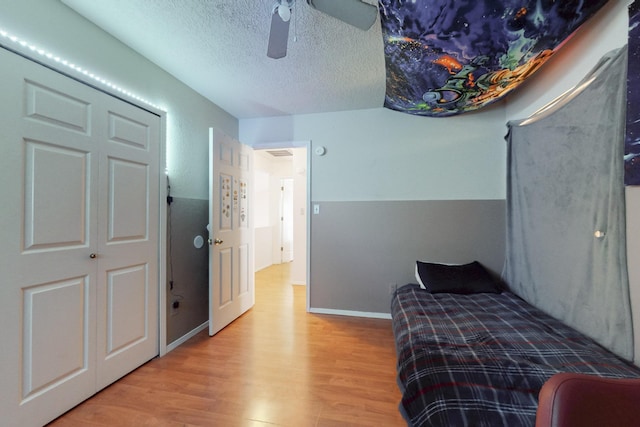 bedroom featuring a textured ceiling, baseboards, ceiling fan, and wood finished floors