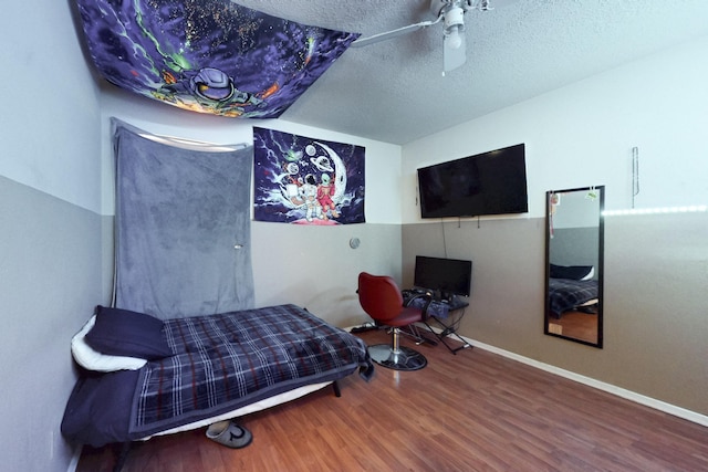 bedroom featuring baseboards, a textured ceiling, wood finished floors, and ceiling fan