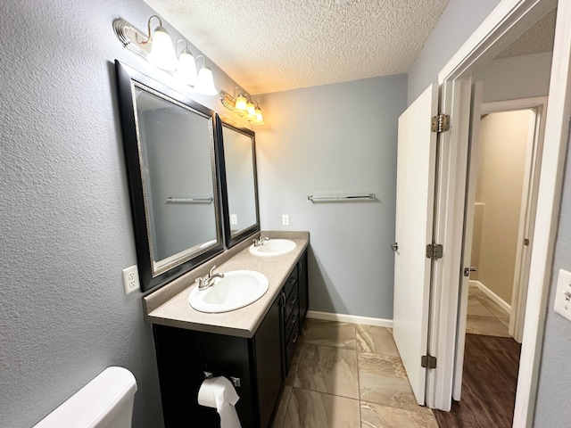 131 Las Ramblas Ave NW, Rio Rancho, NM 87144 - bathroom with toilet, double vanity, a textured ceiling, and baseboards