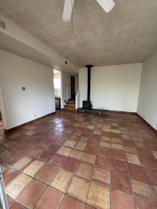 6488 Tahawash St, Cochiti Lake, NM 87083 - spare room featuring baseboards, a textured ceiling, visible vents, and a wood stove
