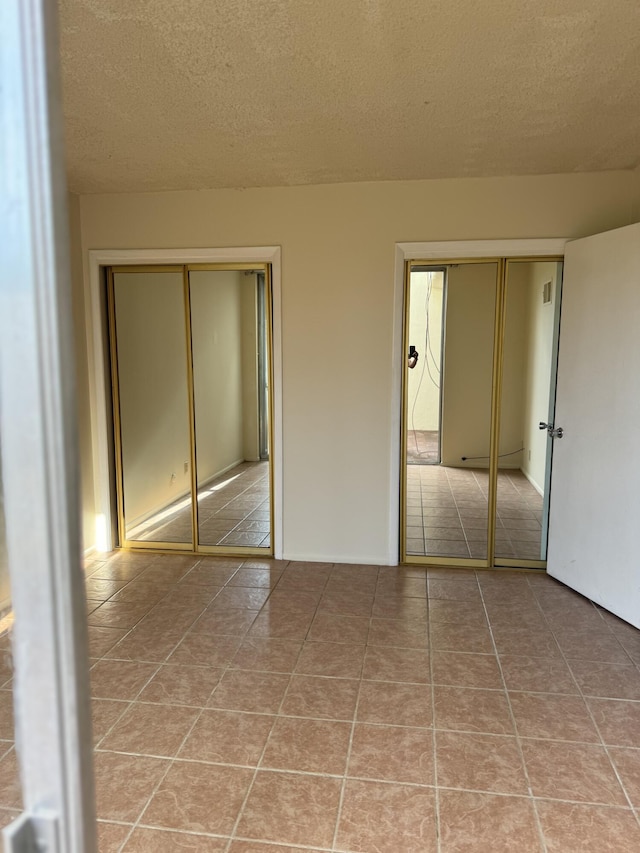 6488 Tahawash St, Cochiti Lake, NM 87083 - unfurnished bedroom featuring multiple closets, a textured ceiling, and light tile patterned floors