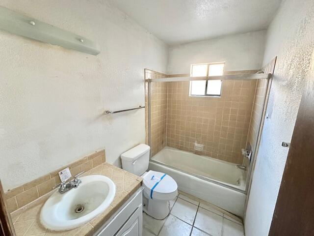 701 Houston Ave, Grants, NM 87020 - bathroom featuring toilet, tile patterned floors, vanity, a textured wall, and shower / bath combination