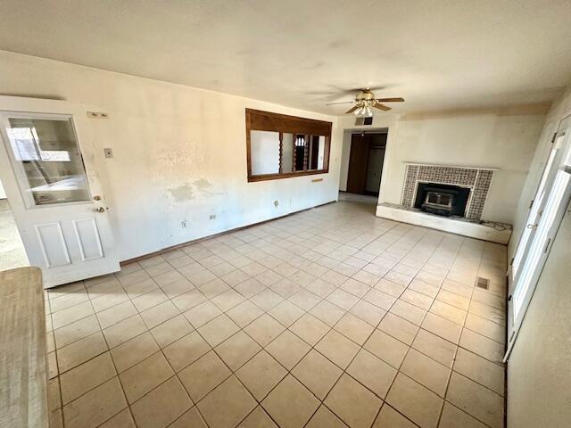 701 Houston Ave, Grants, NM 87020 - unfurnished living room featuring a ceiling fan, a brick fireplace, and tile patterned floors