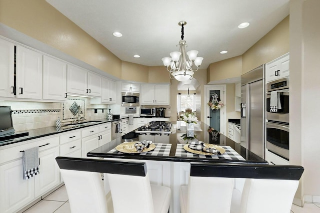 6404 Oak Hill NE, Albuquerque, NM 87111 - kitchen with white cabinetry, backsplash, a kitchen island, dark countertops, and appliances with stainless steel finishes