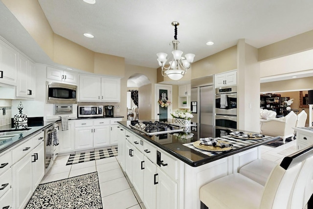 6404 Oak Hill NE, Albuquerque, NM 87111 - kitchen featuring arched walkways, stainless steel appliances, a center island, and dark countertops