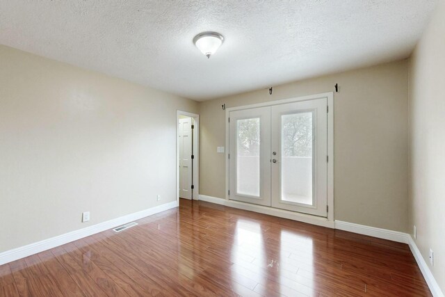 6404 Oak Hill NE, Albuquerque, NM 87111 - empty room featuring a textured ceiling, visible vents, baseboards, wood finished floors, and french doors