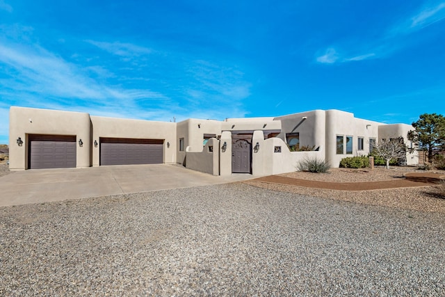 adobe home with stucco siding, a garage, and concrete driveway