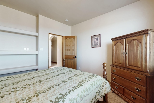 bedroom featuring arched walkways and light colored carpet