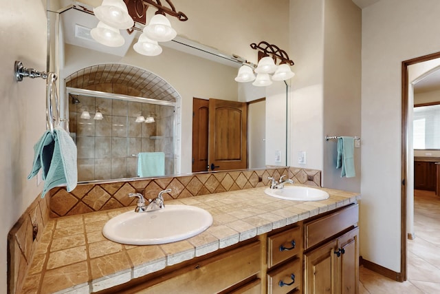 bathroom featuring double vanity, a sink, a stall shower, and backsplash
