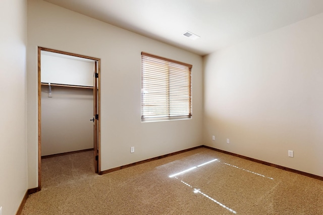 unfurnished bedroom featuring a spacious closet, carpet, baseboards, and visible vents