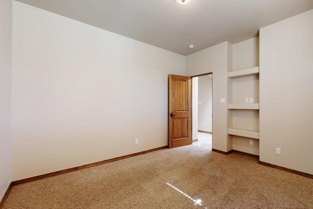 carpeted spare room with built in features and baseboards