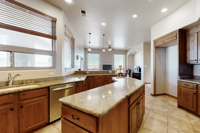 kitchen with a sink, stainless steel dishwasher, brown cabinetry, visible vents, and ceiling fan