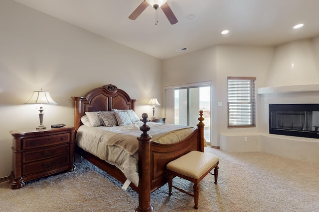 carpeted bedroom featuring recessed lighting, lofted ceiling, a fireplace, and visible vents
