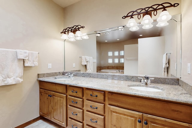 bathroom with double vanity, a sink, baseboards, and a garden tub