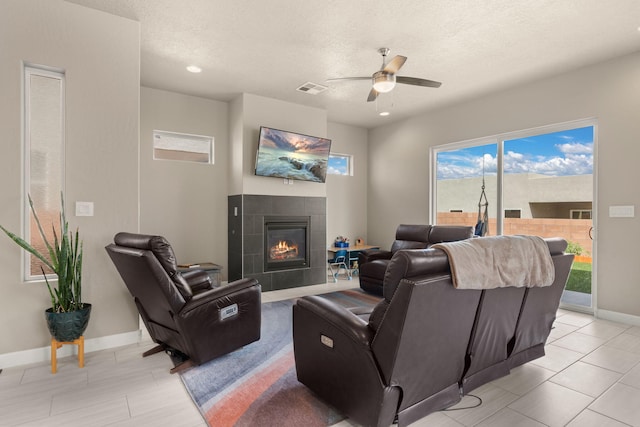 2422 Lynn Rd SE, Rio Rancho, NM 87124 - living area featuring ceiling fan, a fireplace, a textured ceiling, baseboards, and visible vents