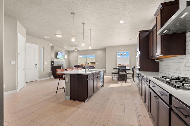 2422 Lynn Rd SE, Rio Rancho, NM 87124 - kitchen with dark brown cabinets, a sink, light countertops, stainless steel appliances, and wall chimney exhaust hood