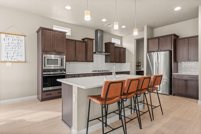 2422 Lynn Rd SE, Rio Rancho, NM 87124 - kitchen featuring a breakfast bar, light countertops, wall chimney exhaust hood, appliances with stainless steel finishes, and backsplash