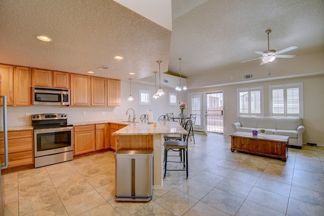 10916 Calandrias St NW, Albuquerque, NM 87114 - kitchen featuring a breakfast bar area, vaulted ceiling, visible vents, a peninsula, and appliances with stainless steel finishes